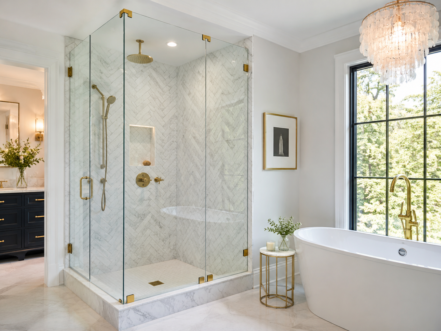 Frameless glass shower enclosure with satin brass hardware and marble herringbone tile